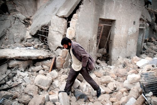 Syrian man walks amid debris